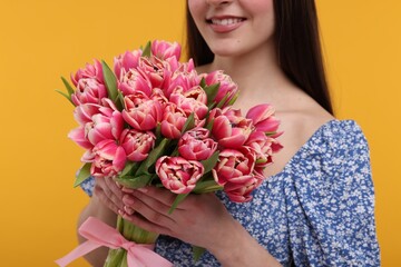 Happy woman with beautiful bouquet on orange background, closeup
