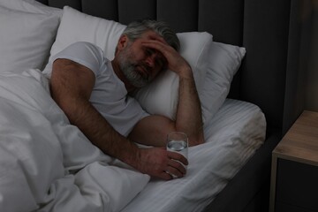 Mature man suffering from headache in bed at night