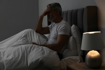 Fototapeta na wymiar Mature man suffering from headache in bed at night