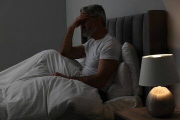 Mature man suffering from headache in bed at night