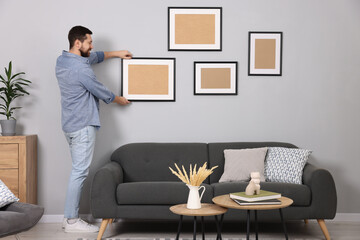 Man hanging picture frame on gray wall at home