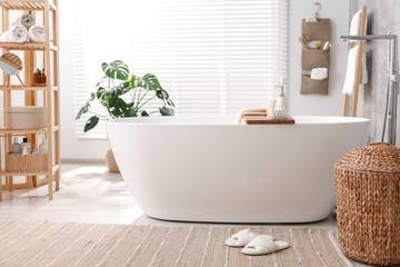 Set of different bath accessories and soap on tub in bathroom