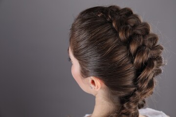 Woman with braided hair on grey background, closeup. Space for text