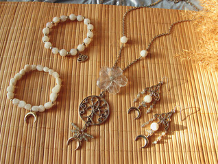 Obraz na płótnie Canvas Delicate jewelry from natural stones adullar (moonstone), crackle agate, quartz, labradorite in Celtic style on a bamboo background.