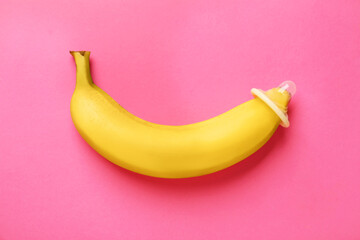 Banana with condom on pink background, top view. Safe sex concept