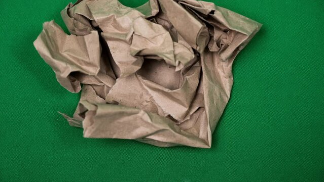 Animation of folding craft paper, freeze frame on green screen, chromakey. Transition from craft paper to green background.