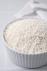 Tapioca pearls in bowl on white tiled table, closeup