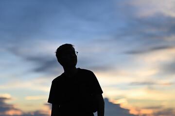 Silhouette of a man with eyeglasses looking on the sky on the mountain, Solo travel concept