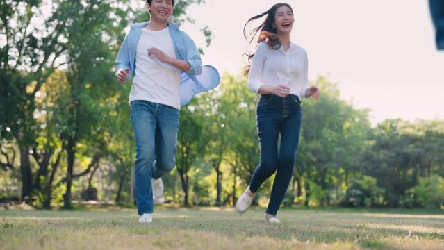 Asian family running together and children playing windmill toy in nature park, Activity on weekend concept
