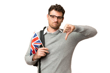 Brazilian man holding an United Kingdom flag over isolated chroma key background showing thumb down...