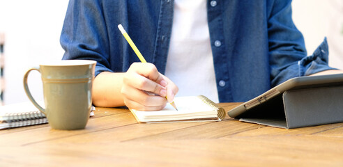 Online studying class, Student man hand writing on notebook while using digital tablet for e...