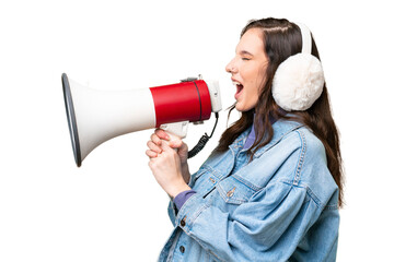 Young caucasian woman wearing winter muffs over isolated background shouting through a megaphone