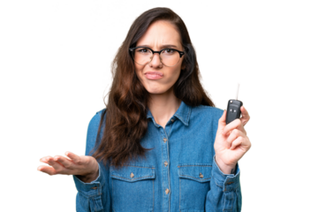 Young caucasian woman holding car keys over isolated background making doubts gesture while lifting the shoulders