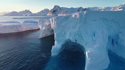 Antarctica huge iceberg with caves and arch in sunset light. A breathtaking scene of Antarctic big...