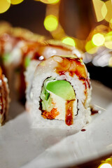 Sushi roll with scallop, cream cheese, masago and avocado against festive lights