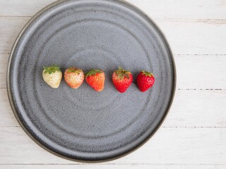 Place the strawberries in a gradient color, ripeness level