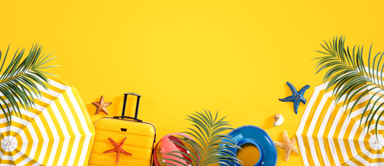 Beach umbrella with summer accessory and luggage on vibrant yellow background with copy space....