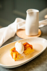 Torrija con bola de helado artesano de vainilla bañado con caldo de vainilla templada en vajilla blanca sobre una mesa de restaurante goumet