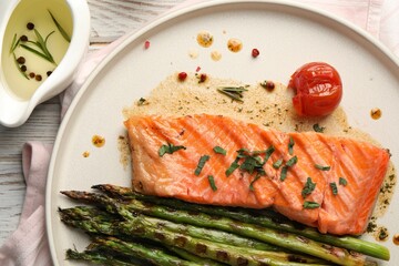 Tasty grilled salmon with tomato, asparagus and spices on table, flat lay