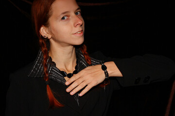 Selfie portrait of a red-haired woman with braids in a black shirt and jacket, decorated with a...