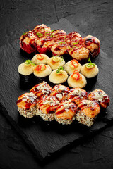 Set of baked sushi rolls with cheese hats and garnishes