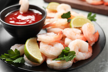 Tasty boiled shrimps with cocktail sauce, parsley and lime on light grey table, closeup