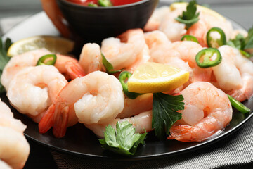 Tasty boiled shrimps with cocktail sauce, chili, parsley and lemon on table, closeup