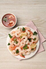 Tasty boiled shrimps with cocktail sauce, chili, parsley and lemon on light wooden table, flat lay