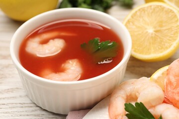 Tasty boiled shrimps with cocktail sauce, chili and parsley on light wooden table, closeup