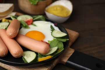 Delicious breakfast with boiled sausages and fried egg served on wooden table, closeup