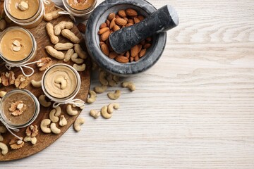 Making nut butters from different nuts on wooden table, top view. Space for text