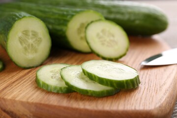Cucumbers and knife on wooden cutting board, closeup