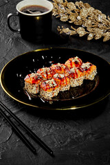 Baked sushi rolls on black platter with golden decor
