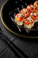 Baked uramaki in sesame with Parmesan crumbs on black and gold platter
