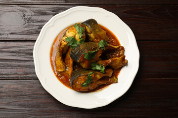 Tasty fish curry on wooden table, top view. Indian cuisine