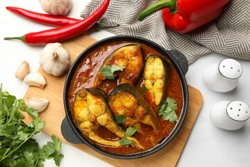 Tasty fish curry and ingredients on white table, flat lay. Indian cuisine