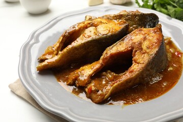 Tasty fish curry on white table, closeup. Indian cuisine