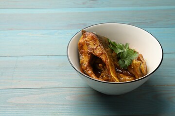 Tasty fish curry on light blue wooden table, space for text. Indian cuisine
