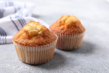 Delicious sweet muffins on light grey textured table, closeup. Space for text