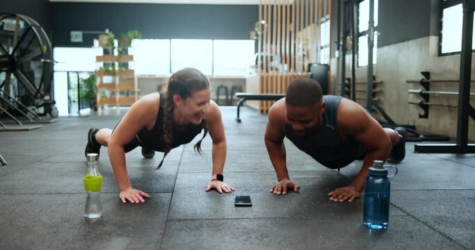 Happy people, fitness and push ups in team exercise or workout together on floor at gym. Interracial man and woman with smile for strength training, biceps and lifting body weight at health club