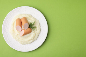 Delicious boiled sausages, mashed potato and dill on green background, top view. Space for text
