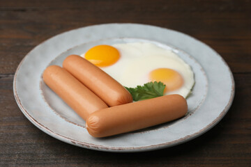 Delicious boiled sausages, fried eggs and parsley on wooden table, closeup