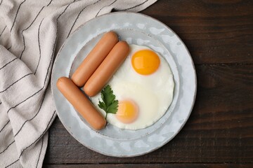 Delicious boiled sausages, fried eggs and parsley on wooden table, top view