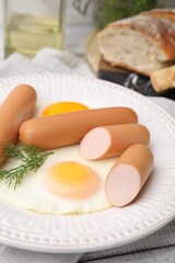 Delicious boiled sausages, fried eggs and dill on table, closeup