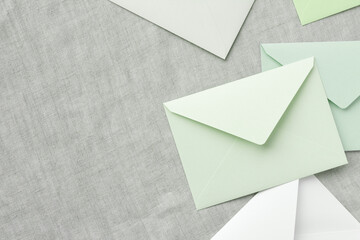 green and white envelopes are randomly placed on a gray tablecloth, leaving a copy space on the...