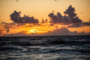 Zachód słońca nad morzem w słoneczny dzień - obrazy, fototapety, plakaty