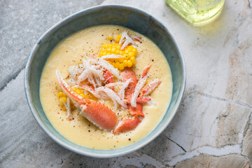 Green bowl with crab and corn soup, horizontal shot on a light-grey granite background, elevated view