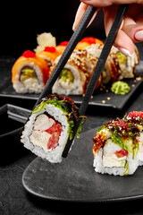 Female hand taking sushi roll with crab meat by chopsticks