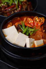 Korean food. Traditional Kimchi soup. on a black wooden background.