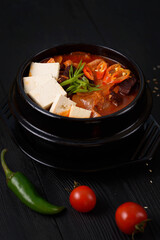Korean food. Traditional Kimchi soup. on a black wooden background.